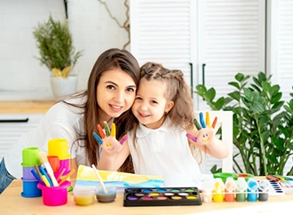 Woman and child painting with colorful paints at a table.
