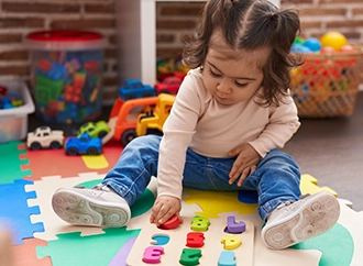 Toddler playing with colorful puzzle pieces on a foam mat.