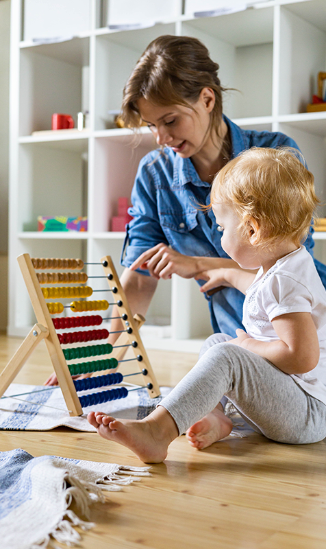 Woman Teaching Child with Abacus in a Day Care Center